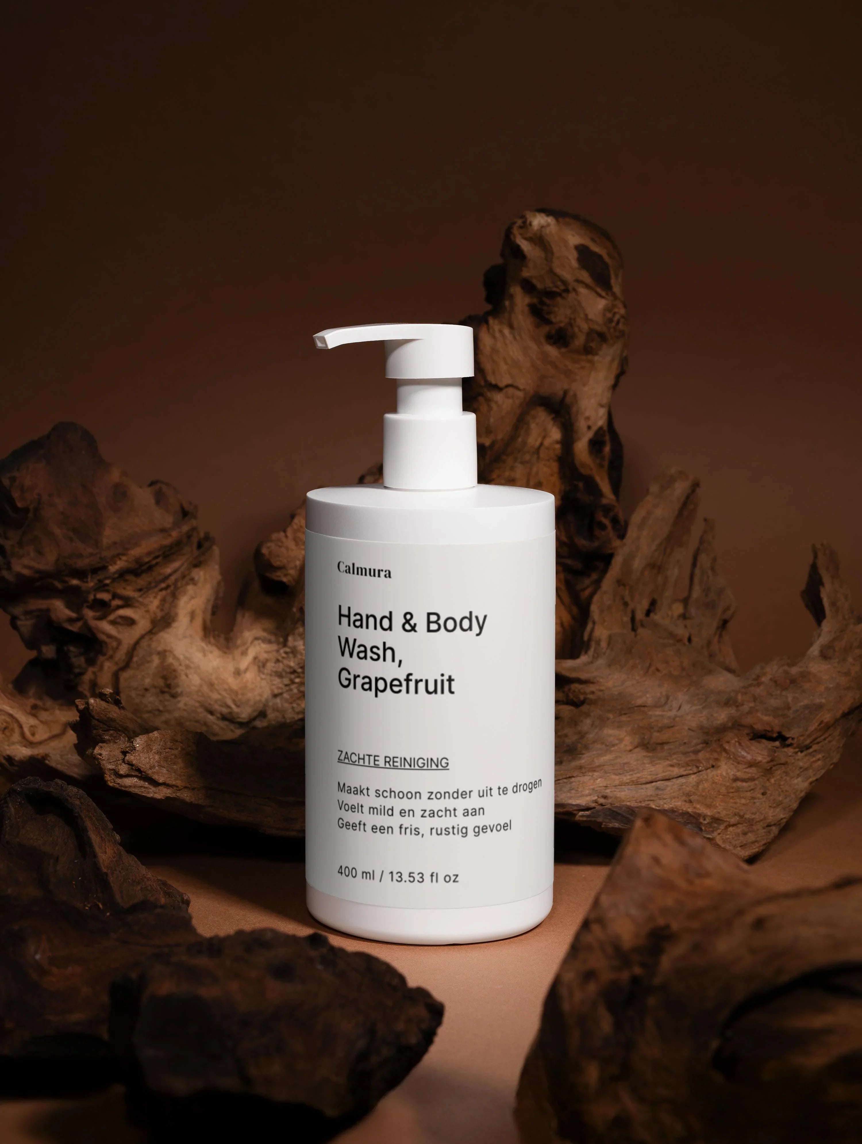 Image of White pump bottle labeled 'Hand & Body Wash, Grapefruit' surrounded by wooden accents against a brown background